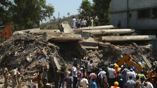 Indian rescue workers and local residents stand near the debris at the site of a building collapse in Thane, on the outskirts of Mumbai last week.